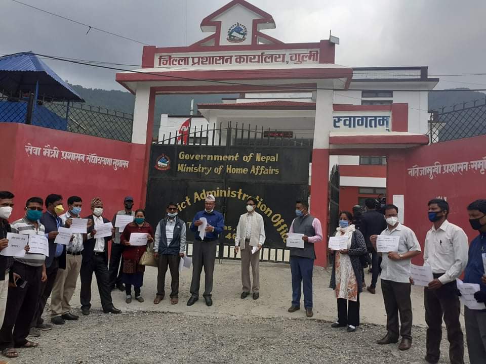 People with face masks and signs standing outside the Ministry of Home Affairs of Nepal