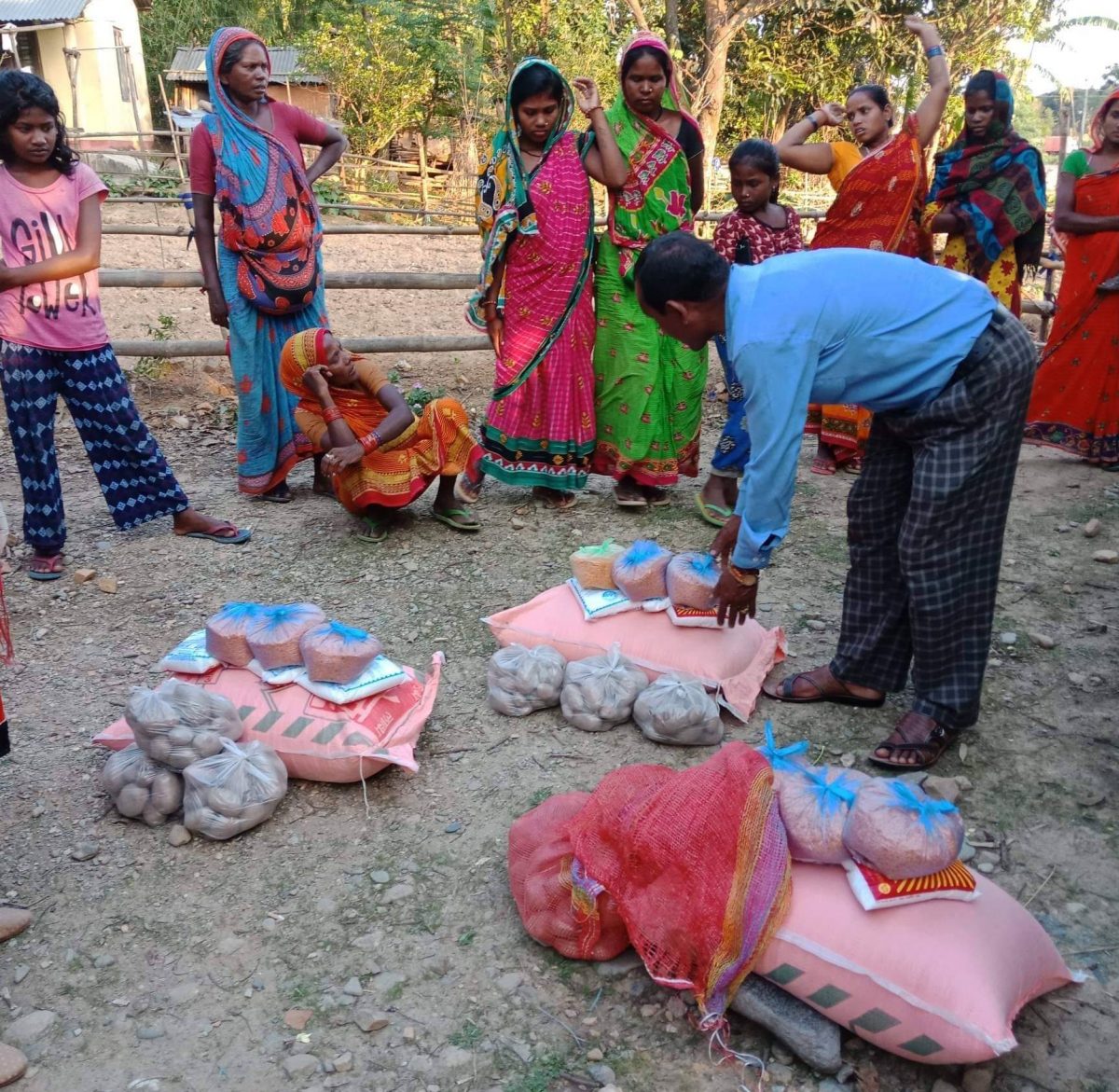 Man bending over relief supplies on the ground and women standing behind.